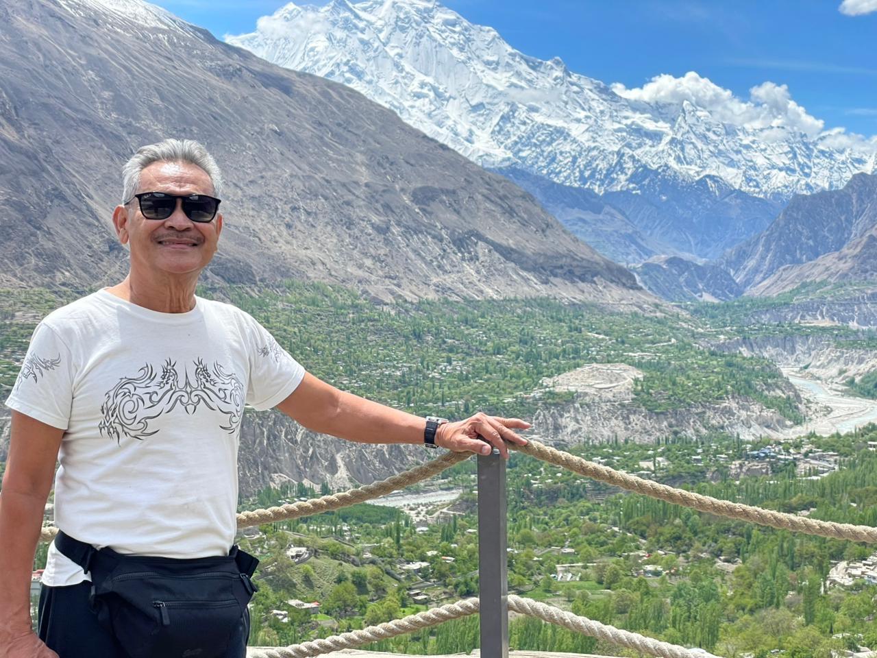 Traveler posing in Hunza Valley with a snow-capped peak in the background